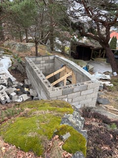 Jordkällarens murade väggar sedda ovanifrån i den kuperade trädgården. Jordkällarens murade väggar sedda ovanifrån i den kuperade trädgården.