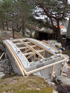 Träreglar och bärverk monteras som form för jordkällarens betongtak. Träreglar och bärverk monteras som form för jordkällarens betongtak.