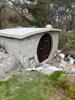Rund mörk trädörr monterad i jordkällaren före naturstensbeklädnad. Rund mörk trädörr monterad i jordkällaren före naturstensbeklädnad.