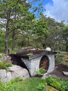 Naturstensklädd jordkällare med grönt tak i skogsträdgård. Naturstensklädd jordkällare med grönt tak i skogsträdgård.
